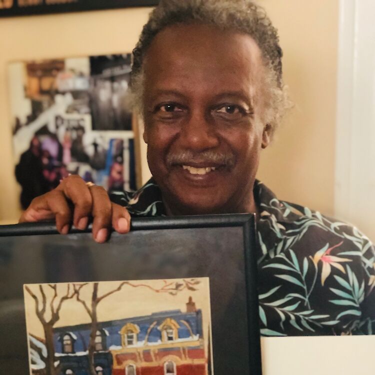 Storyteller Gil Carty holds a painting of a house resembling his great aunt’s house and his Aunt Jean’s portrait. (Photo courtesy of Gil Carty.)