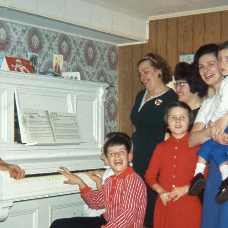 The family around their piano in the basement rec room, Christmas time